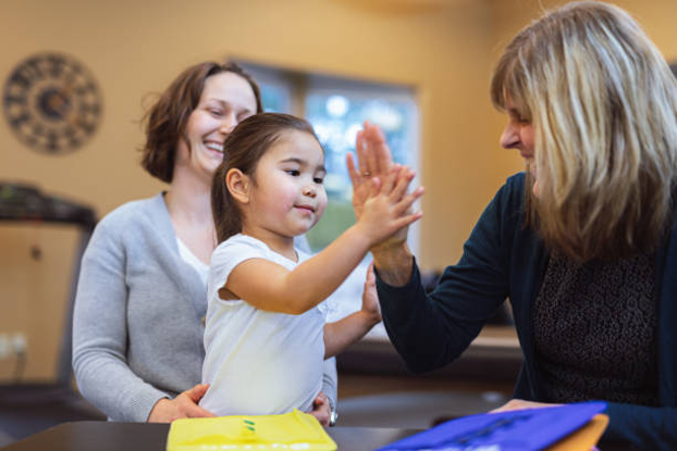 Speech therapist giving a young child a high five during a session