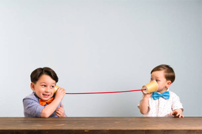 Two children playing with a tin can phone